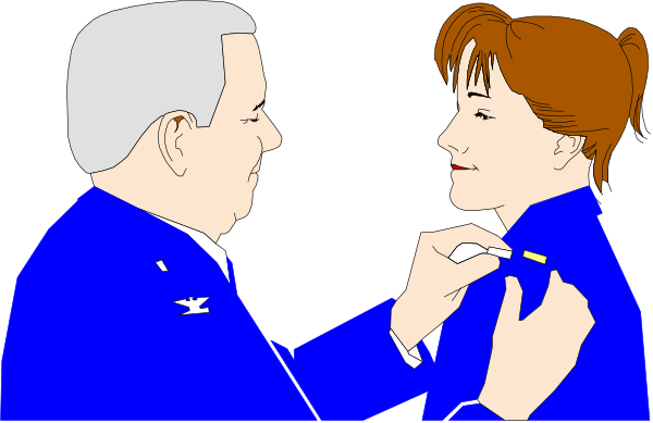 The image shows a man wearing an air force uniform pinning something on another person's jacket while standing next to each other in what appears to be a dark room with blue lighting.