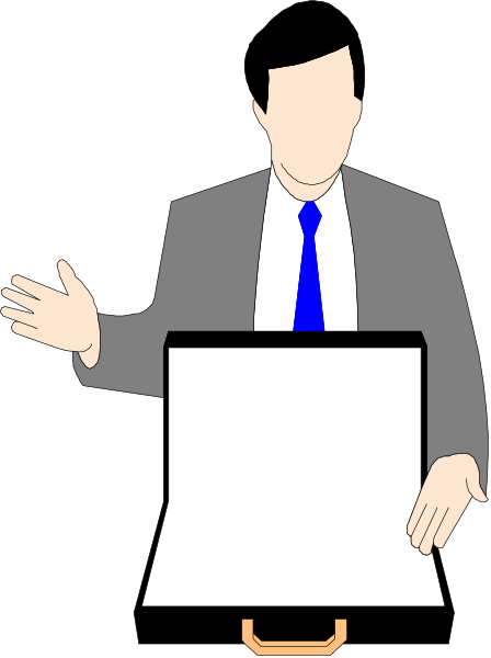 The image shows a man standing behind an easel with papers on it; he is gesturing towards something off-camera while wearing a suit jacket over his shoulder.