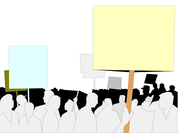The image shows a protest scene with multiple signs held by individuals standing outside at nighttime under dark skies; there is no text on any of these items to provide context for their content.