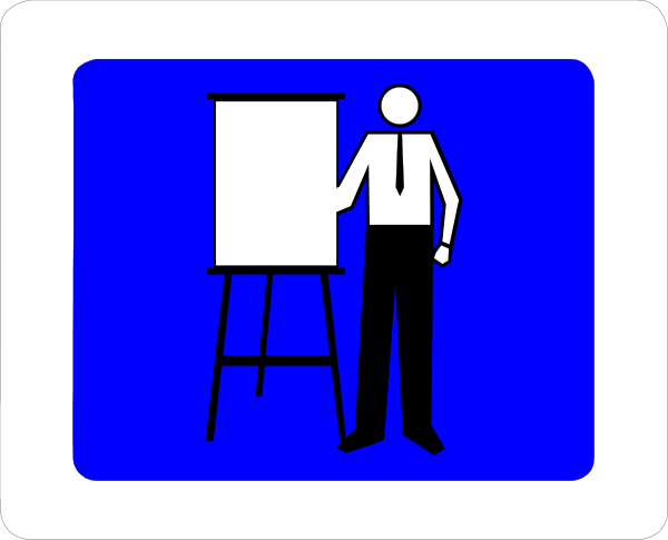 The image shows a blue sign with white text that reads "No Parking" at its top right corner. Below this is an icon of a person standing next to an easel holding chalk in their hand, suggesting teaching activity within restricted parking area.