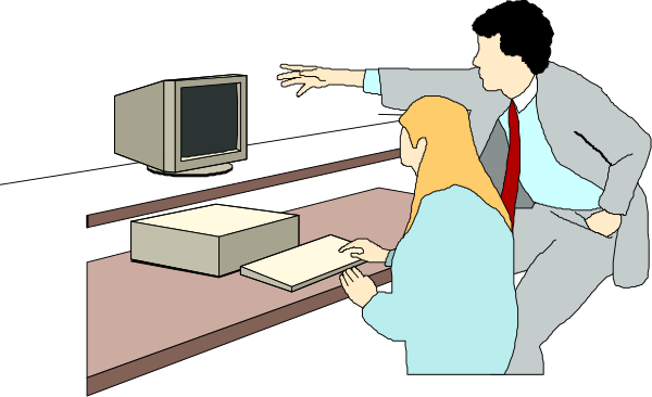 The image shows a man standing at an office desk with two computer monitors on it; he is pointing to something off-screen while gesturing towards another person who appears surprised by his action.