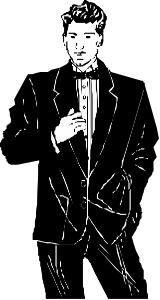 The black and white photo shows a man dressed as Batman standing against a dark background with his hands on hips.