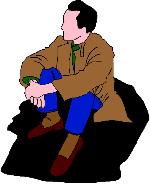 The image shows a man sitting on his knees with hands clasped together over his lap; he is wearing jeans and brown shoes. He has short hair and appears to be in thoughtful repose against a dark background, which does not provide any additional context about location or setting beyond being indoors.