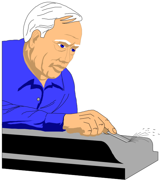 The image shows a man sitting at an office desk with his hands on top of some papers; he appears to be reading them closely while wearing glasses.