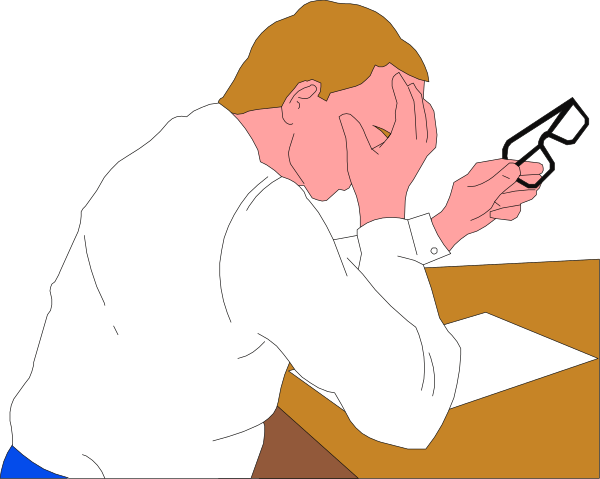 The image shows a man sitting at his desk with papers spread out before him; he is holding his head on both hands in frustration while looking downward towards them.