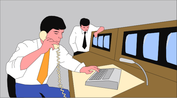 The image shows a man sitting at an office desk with multiple computer monitors behind him; he is talking on his phone while looking downward towards it. Another person stands in front of one monitor to their left, also engaged in conversation over another telephone handset. Both individuals appear focused and are dressed professionally.