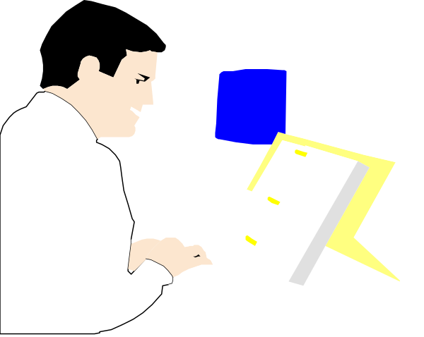 The image shows a man sitting at his desk with an open laptop computer on it; he is looking down towards something off-screen to his right while holding what appears to be papers in front of him.