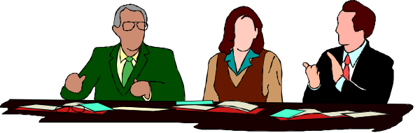 The image shows a group of four individuals seated around a table with papers on it; two men appear to be speaking while gesturing towards each other, one woman is attentively listening, and another man seems to be observing them from behind. They all seem engaged in an animated discussion or meeting at what looks like a conference setting.