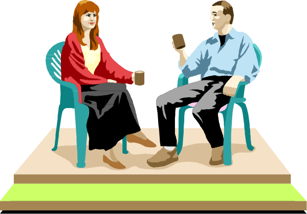 The image shows a man sitting on an armchair with his legs crossed atop another chair while holding what appears to be a book in one hand; next to him is a woman seated comfortably cross-legged, also engaged in reading from her own copy of the same book. They are both indoors and appear relaxed as they enjoy their shared activity together on an unseen stage or platform with no visible audience present.