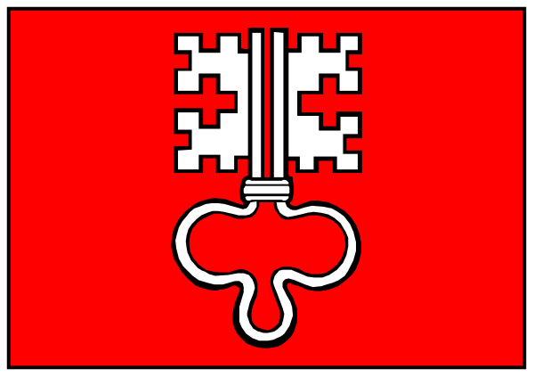 The image shows a red key with an abstract design on it hanging from what appears to be a hook above a white door frame in front of which is a gray wall.