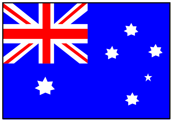 The flag of Australia with a British Union Jack on it flying over an Australian cityscape at nighttime.