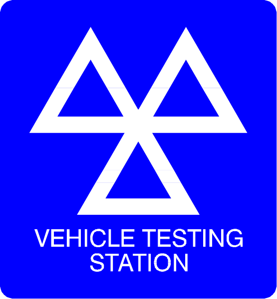 The image shows a blue sign with white text that reads "VEHICLE TESTING STATION" on top of another smaller square-shaped sign featuring an orange triangle symbolizing caution, indicating it's for vehicle testing station only.