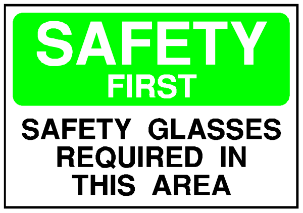 The image shows a sign with text that reads "SAFETY FIRST" at top followed by instructions to wear safety glasses in this area if required upon entry into it.