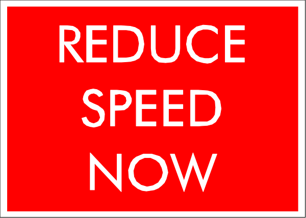 The image shows a red sign with white text that reads "REDUCE SPEED NOW."
