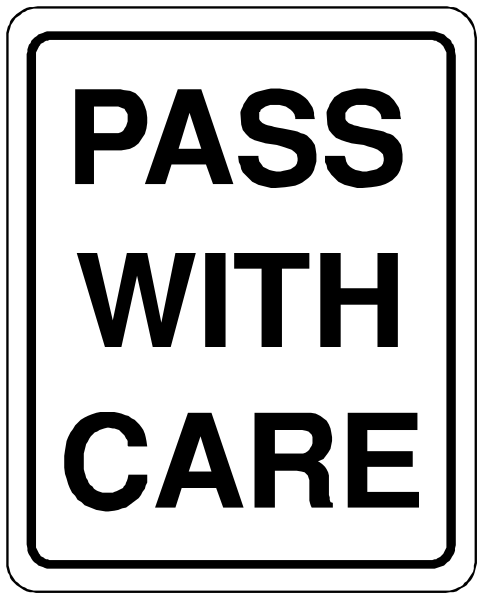 The image shows a black sign with white text that reads "PASS WITH CARE."