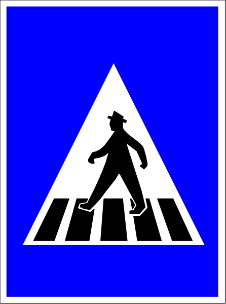 The image shows a blue sign with white text featuring an icon of a person walking across a crosswalk on top right corner.
