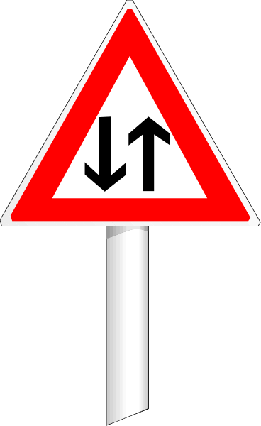 The image shows a red traffic sign with white arrows pointing upwards on it against an out of focus background that appears to be taken from another photo due to its blurriness.