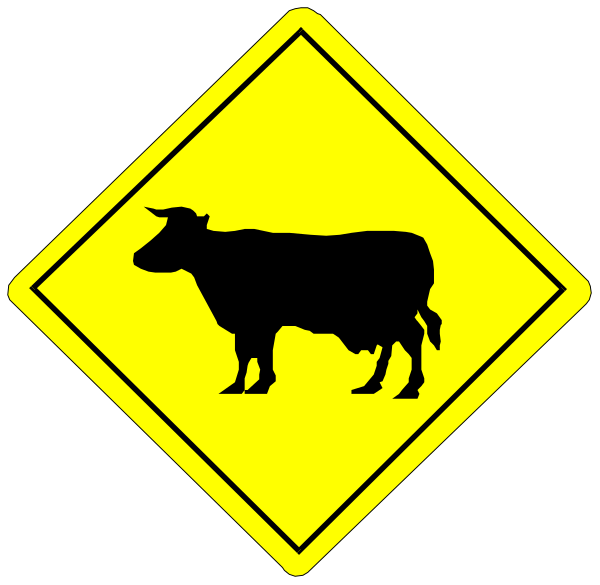 The image shows a yellow hazard sign with black text warning of cattle crossing ahead on an otherwise plain background.