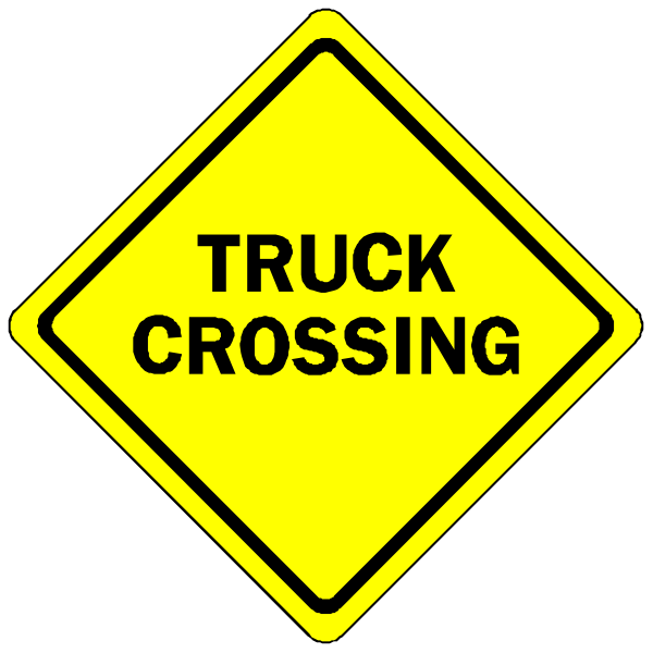 The image shows a yellow diamond sign with black text that reads "TRUCK CROSSING" on it.