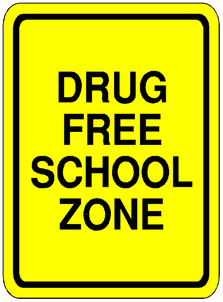 The sign says "DRUG FREE SCHOOL ZONE" on a yellow background with black text.