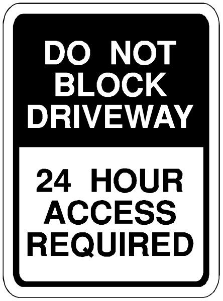 The sign says "do NOT block driveway" with a 24 hour access requirement below it. It is placed on top of another smaller white sticker that reads "required." There's also an arrow pointing to the right, indicating directional flow for traffic or pedestrians in this area. This image appears to be taken from above and slightly angled towards us as we look at the sign.