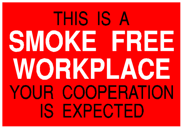 The image shows a red sign with white text that reads "This is a smoke free workplace" atop another smaller sign below it stating "Your co-operation is expected."