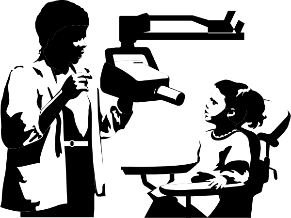 The black and white photo shows a classroom scene with three individuals: an adult standing at the front of the room gesturing towards two students seated in desks facing each other; there is no text present on this image, which focuses solely on their interaction within the educational setting.