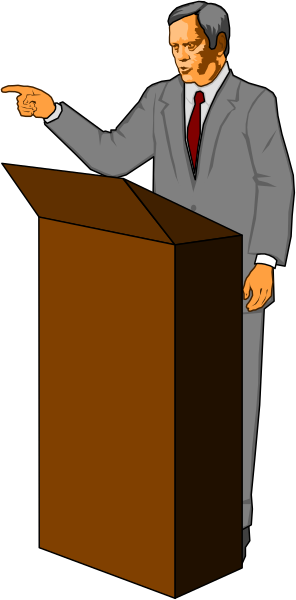 The image shows a man standing at a podium with his hand raised as if gesturing to an audience; he is wearing a suit jacket over what appears to be formal attire underneath.