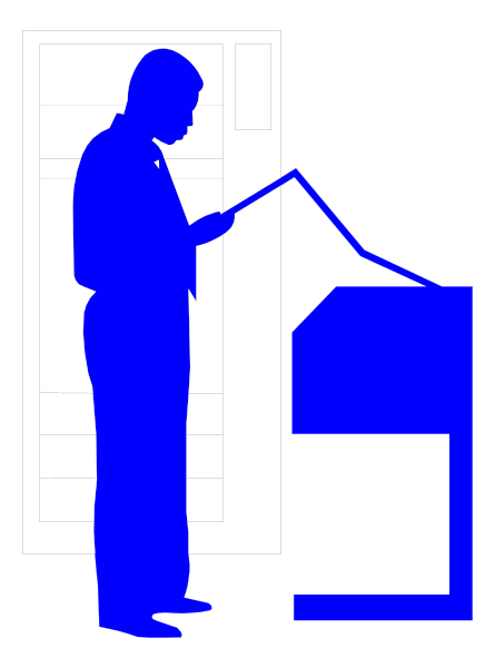 The image shows a man standing at an open podium with papers on it; he is holding what appears to be a microphone in his hand while looking downward towards something out of frame.