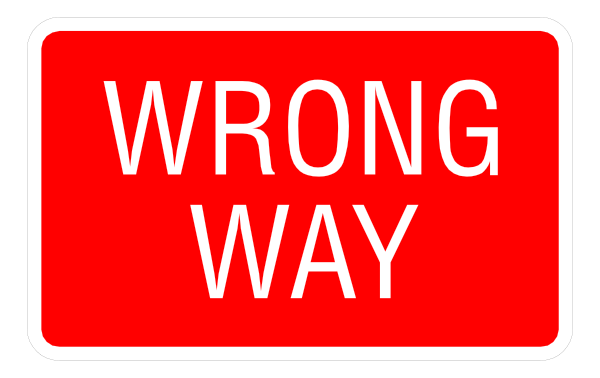 The image shows a red street sign with white text that reads "WRONG WAY" on it against an indistinct background.