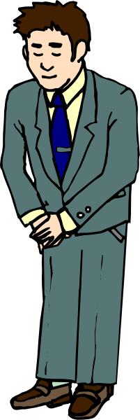 The image shows a man standing against a gray background with his hands behind him; he is wearing a suit jacket over an unseen shirt, has short hair, wears glasses on top of his head, and appears to be looking downwards slightly as if observing something out of frame or in the distance.