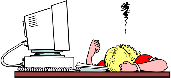 The image shows a person lying on their stomach with arms crossed over head atop an office desk next to computer equipment including monitor, keyboard, mouse, phone, papers, books, scissors, stapler and pen holder in front of them; there is also a cup near the edge of the table.