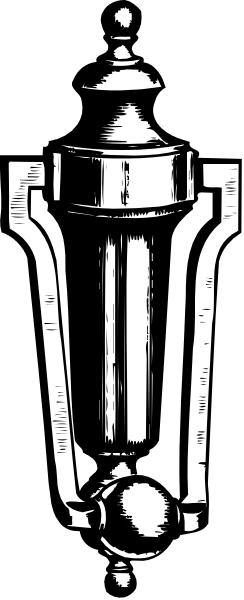 The black and white photo shows a vintage oil lamp with an intricate design on its body placed against a dark background.