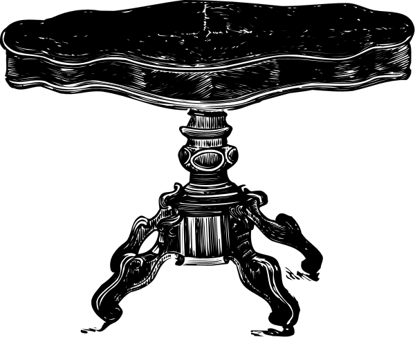 The black and white photo shows a table with an intricate design on its legs against a dark background.