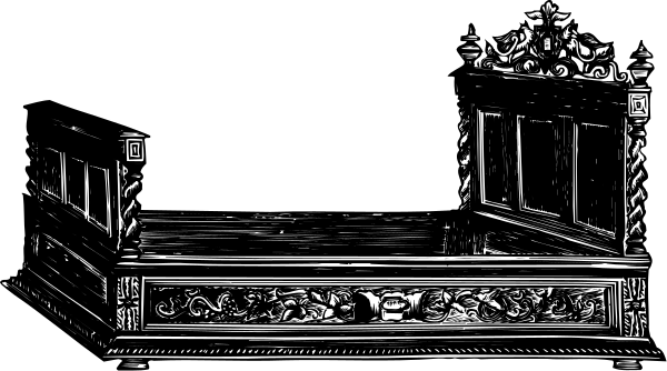 The black and white photo shows a simple bed with carved details on top of it against an indistinct background.