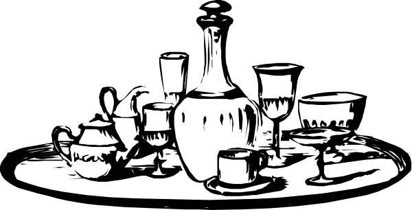 The black and white photo shows a table with various items on it including bottles of alcohol, wine glasses, cups, bowls, vases, candles, books, and other decorative objects such as figurines and small sculptures.